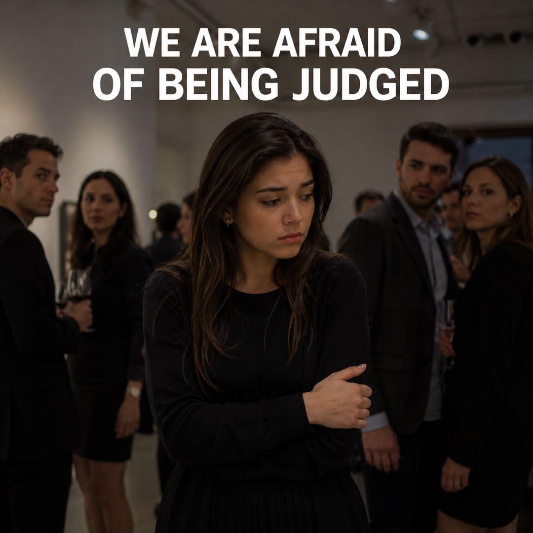 A person in black standing in a room with other people Description automatically generated